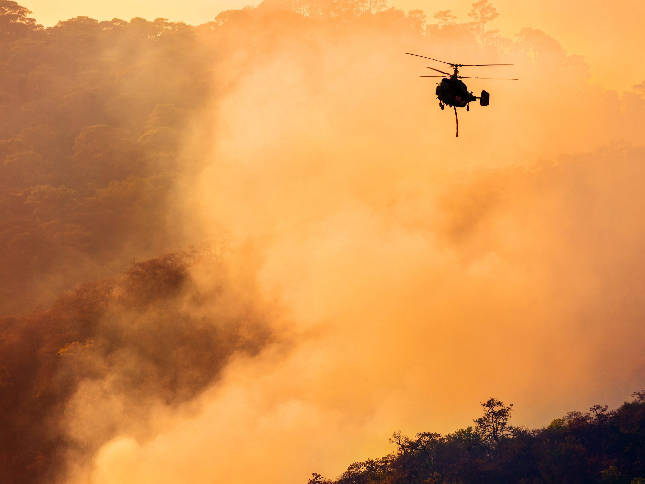 A helicopter drops water on a fire in the Congo Basin