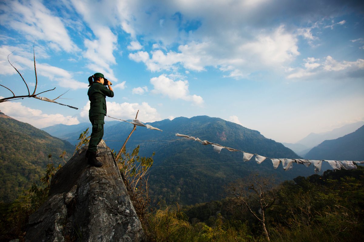 Photograph of Singye taking pictures  from the top of a hill overlooking the forested hills of Bhutan’s Royal Manas National Park