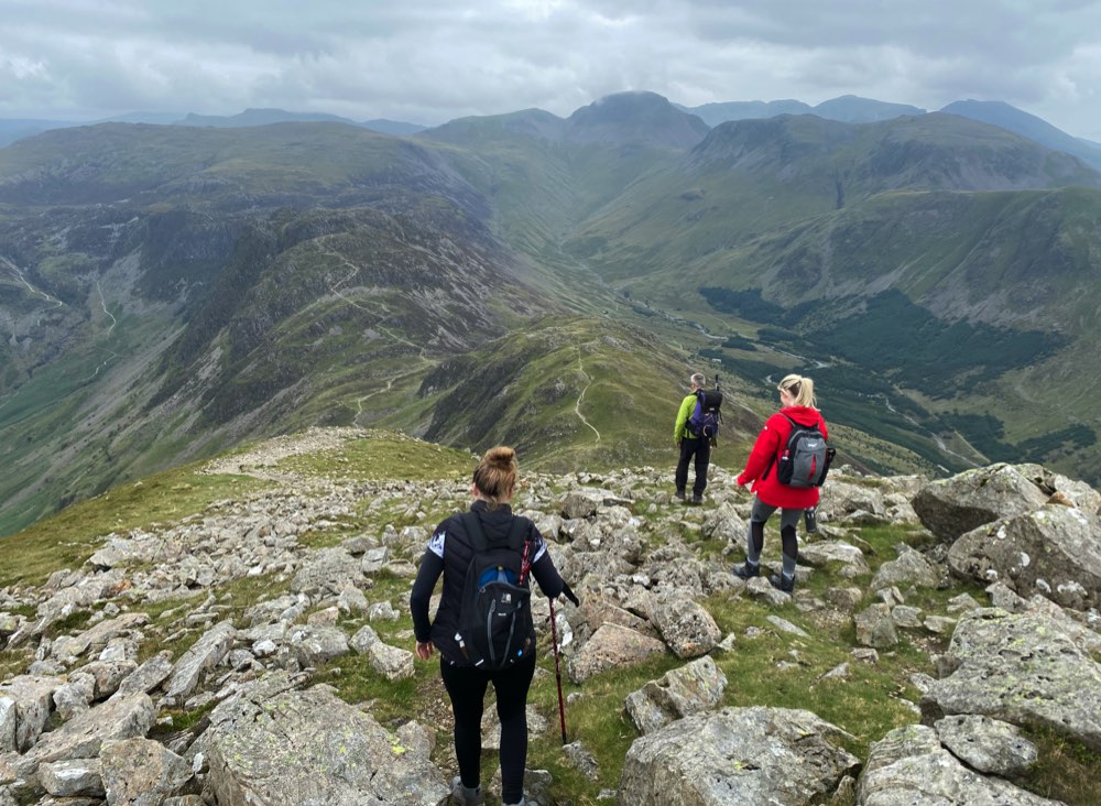 A small group of walkers stand on top of a rocky hill