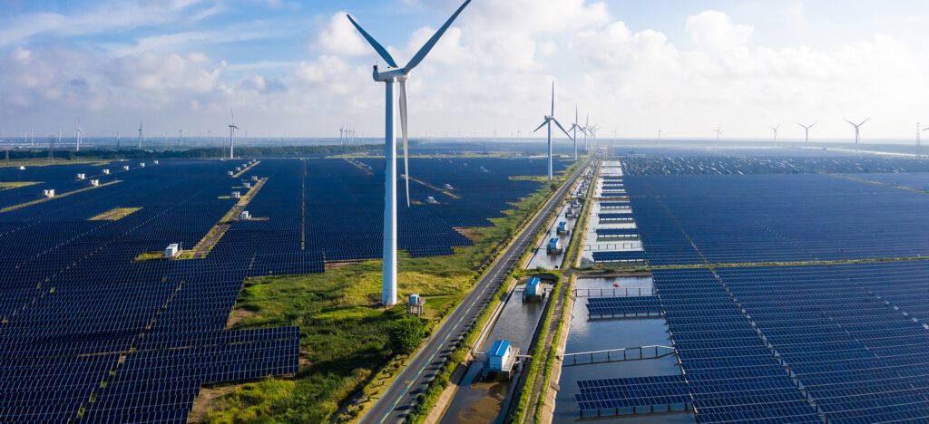 An enhanced image shows huge fields of solar panels with wind turbines standing among them