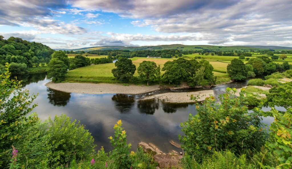 An aerial photo shows a river meandering through a UK landscape of green fields and trees