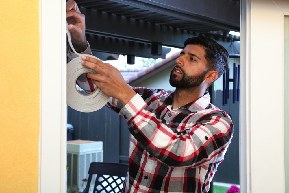 A man fixes insulation tape around the frame of a door