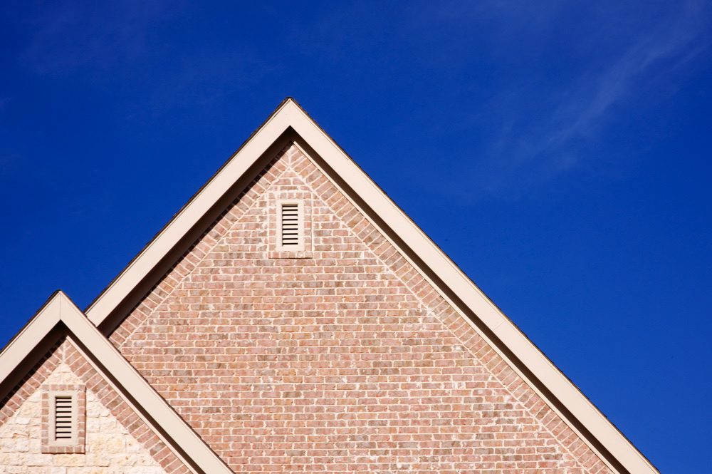 Ventilation bricks are shown at the top of the gable end of a house, against a dark blue sky