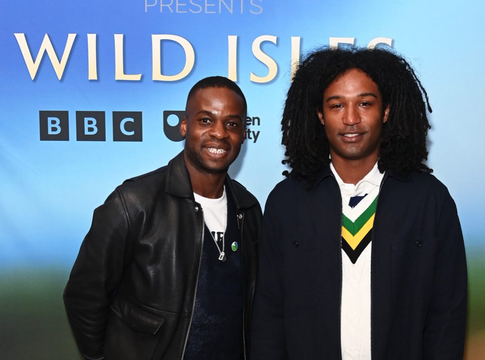 Ollie Olanipekun and Nadeem Perera stand in front of a large poster promoting the Wild Isles TV series