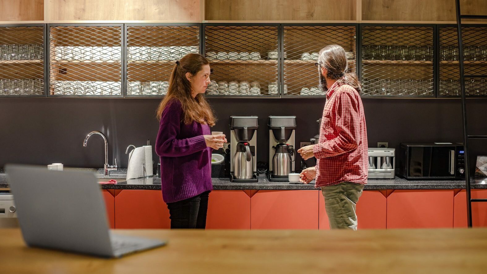 Woman and man having a chat in an office kitchen