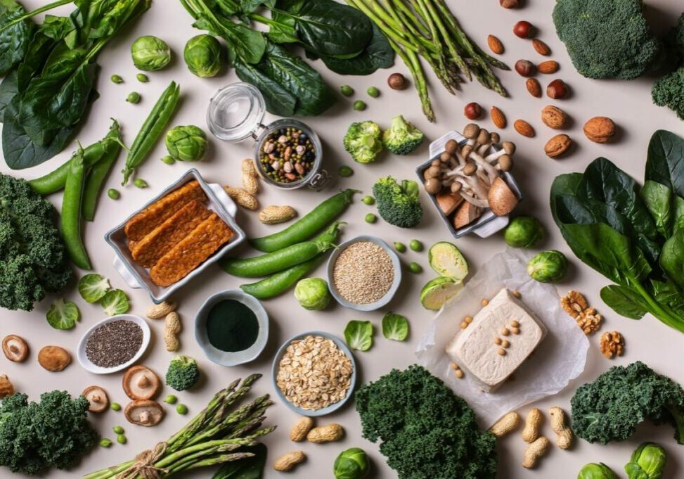 An overhead shot of a spread of nuts, seeds, leafy green vegetables and tofu