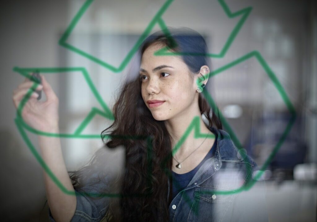 Germany, Cologne, Young woman drawing recycling symbol on glass