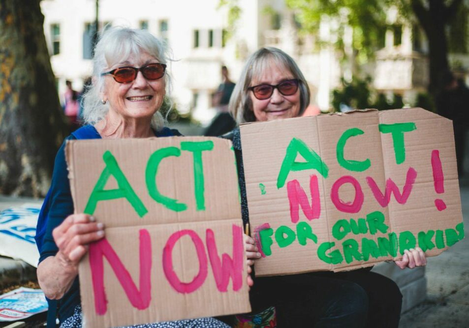Two women hold signs calling for climate action at a protest in London