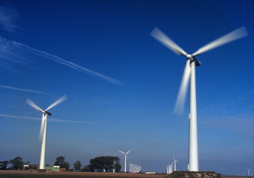 Rows of wind turbines against a blue sky